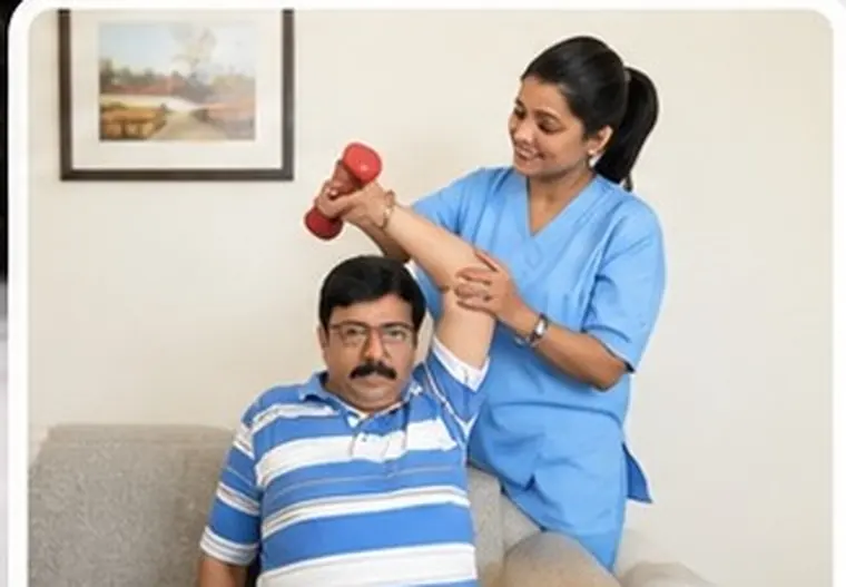 A physiotherapist guiding a senior through an arm exercise with a dumbbell